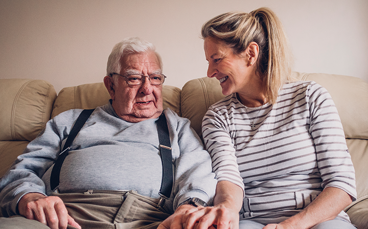 caregiver and father sitting on couch at home